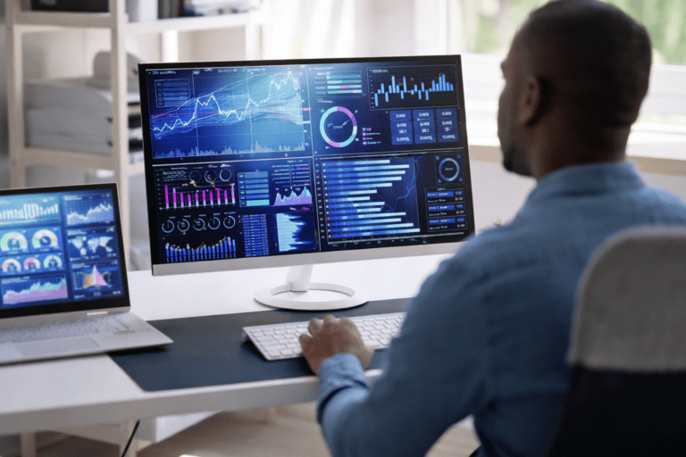 Data Analyst Reviewing Healthcare Performance Dashboards on Multiple Computer Screens