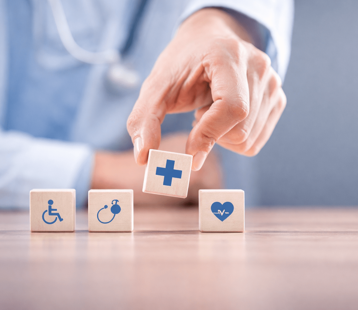 Hand Placing Medical Icon Blocks Representing Healthcare Services and Patient Care