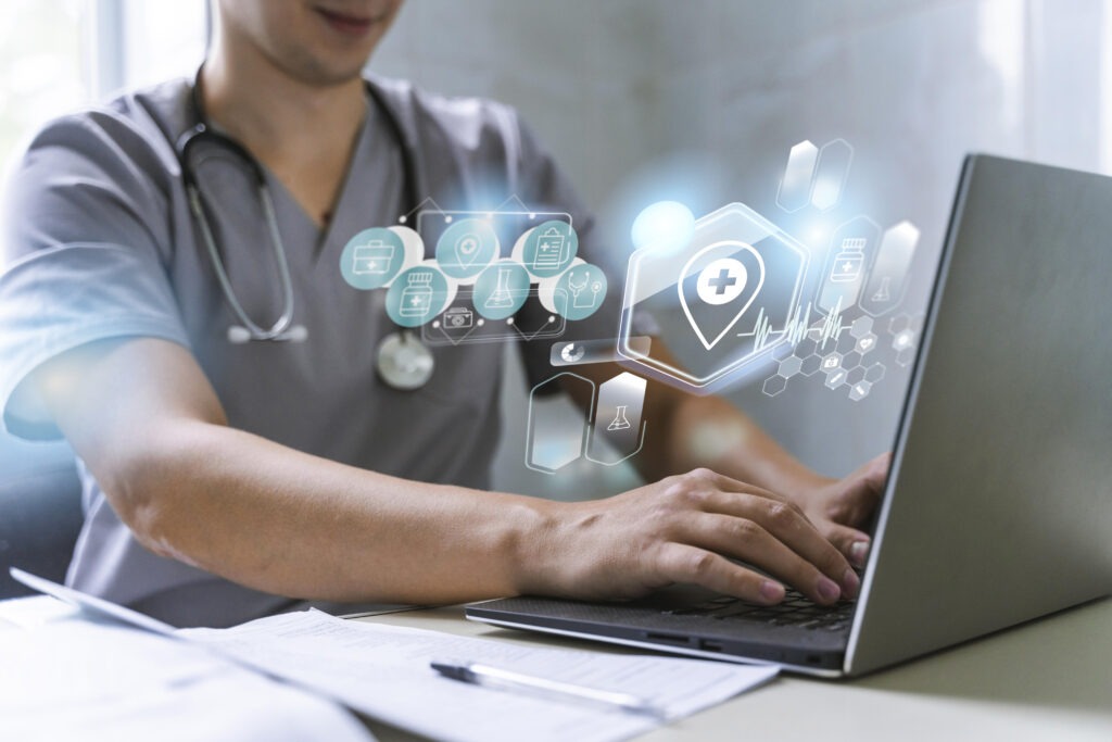 A healthcare professional in scrubs engages with a laptop, surrounded by digital health icons, illustrating the integration of technology in healthcare.